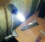 Горит миниатюрная диодная лампа, вставленная вместо люминесцентной в настольный светильник